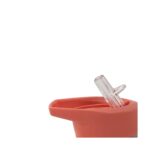 Close-up of a pink silicone cup or pot with a clear plastic clip resting on its rim.