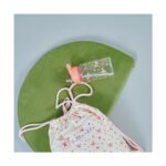 Floral-patterned drawstring bag with pink straps on a green round mat, beside a clear water bottle with a pink lid and flower decals.